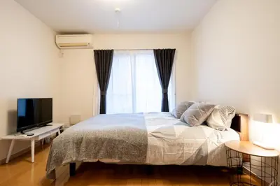 a bedroom with a bed with a television and a window at Belle Lead 106 in Tokyo