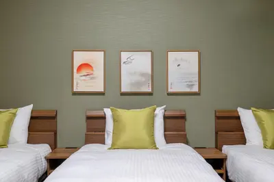 two beds in a room with three pictures on the wall at HOTEL KOMACHI TOKYO Higashi Nippori in Tokyo