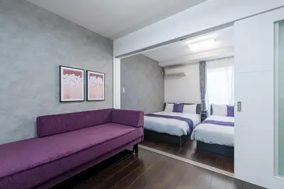 a hotel room with two beds and a couch at HOTEL KOMACHI TOKYO Higashi Nippori in Tokyo
