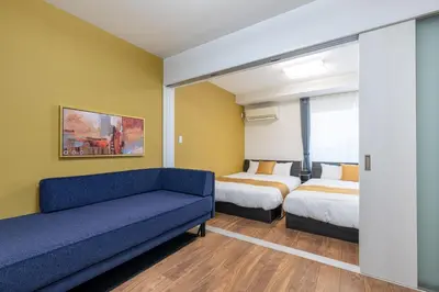a hotel room with two beds and a couch at HOTEL KOMACHI TOKYO Higashi Nippori in Tokyo