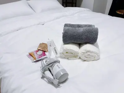 a white bed with a phone and towels on it at \u30b5\u30af\u30e9\u30b7\u30e3\u30c9\u30a6\u6771\u6c60\u888b in Tokyo