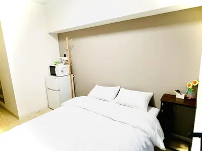 a bed with white sheets and pillows in a room at \u30b5\u30af\u30e9\u30b7\u30e3\u30c9\u30a6\u6771\u6c60\u888b in Tokyo