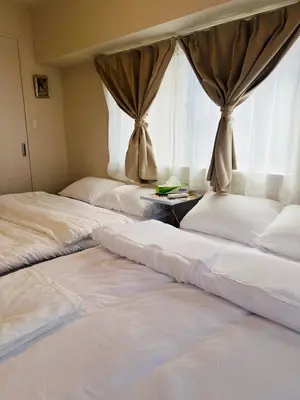 two beds in a room with a window at Ueno Uguisudani Tokan in Tokyo