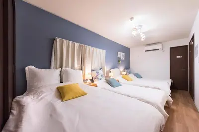 three white beds in a room with blue walls at Wakabayashi house in Tokyo