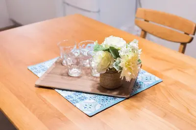a wooden table with a vase of flowers and glasses at Wakabayashi house in Tokyo