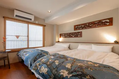 a bedroom with two beds and a desk and a window at \u6674\u30ec\u5c4b\u6d45\u8349 Hareya Asakusa in Tokyo