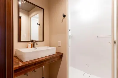 a bathroom with a white sink and a mirror at \u6674\u30ec\u5c4b\u6d45\u8349 Hareya Asakusa in Tokyo
