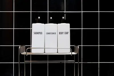 a black tiled wall with three white bottles on a shelf at \u6674\u30ec\u5c4b\u6d45\u8349 Hareya Asakusa in Tokyo