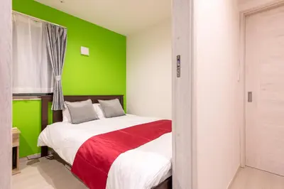 a bedroom with a green accent wall and a bed at Detached house in Oshima 4chome, one train ride to Shinjuku \u5927\u5cf64\u4e01\u76ee in Tokyo