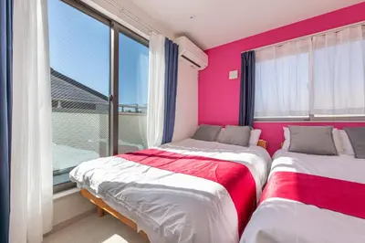 two beds in a room with pink walls and windows at Detached house in Oshima 4chome, one train ride to Shinjuku \u5927\u5cf64\u4e01\u76ee in Tokyo