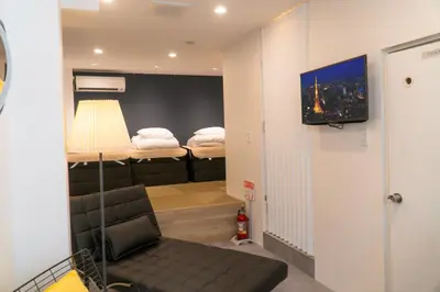 a room with a bed and a couch and a television at YadoyaTamachi 101 in Tokyo