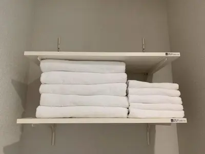 a stack of towels on a shelf in a bathroom at PRISM Inn Tateishi in Tokyo