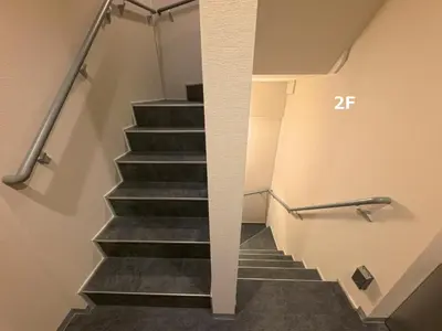 a staircase with black treads and a wall with a stair railing at PRISM Inn Tateishi in Tokyo
