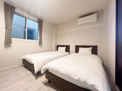 two beds in a bedroom with a window at PRISM Inn Tateishi in Tokyo