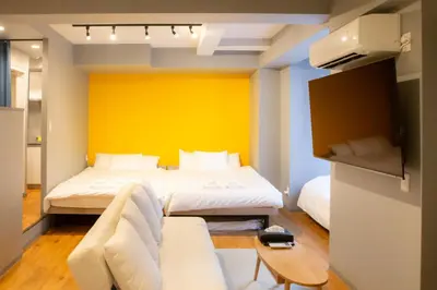 a bedroom with two beds and a yellow wall at \u30a8\u30b3\u30ed\u65b0\u5bbf\u7b2c\u4e8c\u30d3\u30eb in Tokyo