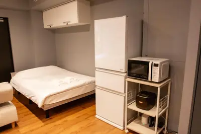 a small room with a bed and a microwave at \u30a8\u30b3\u30ed\u65b0\u5bbf\u7b2c\u4e8c\u30d3\u30eb in Tokyo