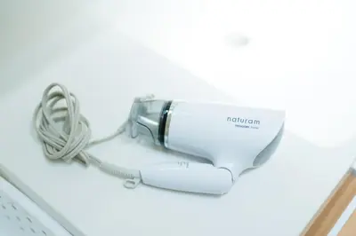 a white electric hair dryer sitting on a table at Tokyo Platinum Comfort in Tokyo