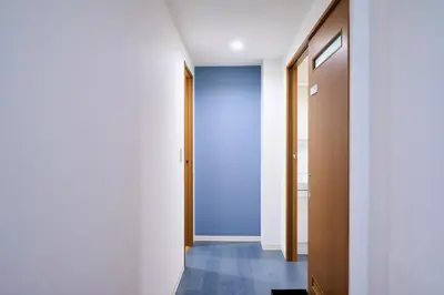 a hallway with white walls and a blue door at willcourt in Tokyo