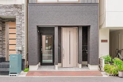a brown brick building with a pink door at Ueno home2 10-minute walk from Ueno Station, 4-minute walk from Inaricho Station, 10-minute walk to Asakusa, 1F in Tokyo
