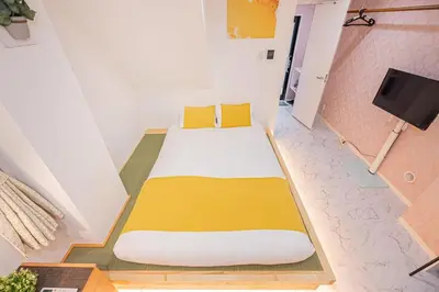a bedroom with a bed with yellow pillows and a tv at Ueno home2 10-minute walk from Ueno Station, 4-minute walk from Inaricho Station, 10-minute walk to Asakusa, 1F in Tokyo