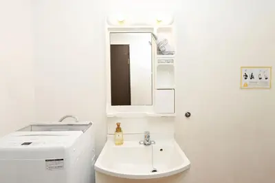 a white bathroom with a sink and a mirror at Shinjuku family apartment in Tokyo