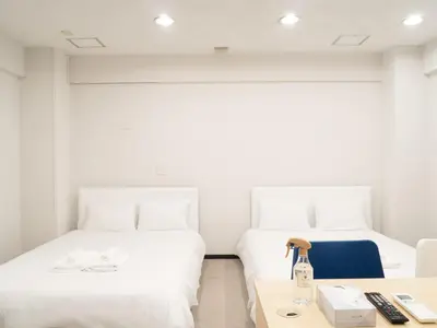 two beds in a room with a desk and a table at Shinjuku family apartment in Tokyo