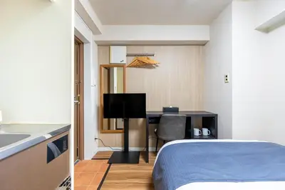 a bedroom with a bed and a desk with a television at Sleep Inn Gotanda in Tokyo