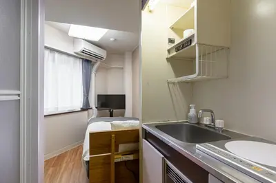 a small bathroom with a sink and a bed at Sleep Inn Gotanda in Tokyo