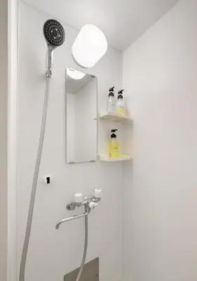 a shower in a bathroom with a mirror at Sleep Inn Gotanda in Tokyo