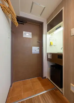 a brown door in a room with a kitchen at Sleep Inn Gotanda in Tokyo