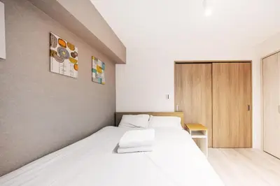 a bedroom with a white bed and a wooden cabinet at 203 8 min walk to Ikebukuro 6 min walk to Kanamecho Station 25m Max 2 people Direct access to Tokyo, Shinjuku, Shibuya, Ueno in Tokyo