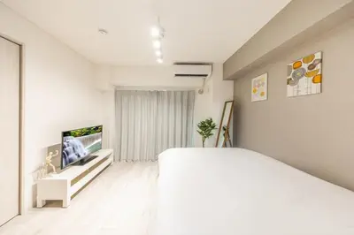 a white bedroom with a large bed and a flat screen tv at 203 8 min walk to Ikebukuro 6 min walk to Kanamecho Station 25m Max 2 people Direct access to Tokyo, Shinjuku, Shibuya, Ueno in Tokyo