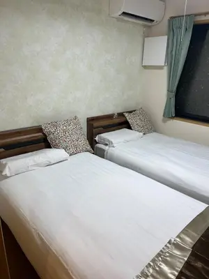 two twin beds in a room with a window at Sky Tree Stay Hotel, 4-minute walk from Keisei Hikifune Station, detached house with parking, very convenient location in Tokyo