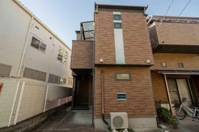 a tall brick building with a gate in front of it at Sky Tree Stay Hotel, 4-minute walk from Keisei Hikifune Station, detached house with parking, very convenient location in Tokyo