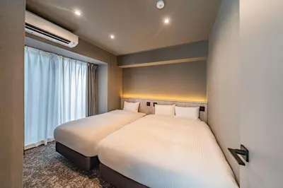 two beds in a small room with a window at Apartment Hotel 11 Asakusa 2 in Tokyo