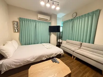 a living room with a bed and a couch at \u30b3\u30fc\u30dd\u5ca1\u5d0e301 in Tokyo