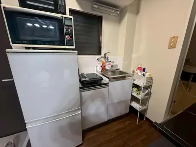 a small kitchen with a microwave and a refrigerator at \u30b3\u30fc\u30dd\u5ca1\u5d0e301 in Tokyo