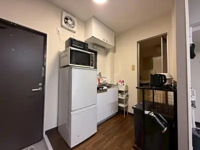 a small kitchen with a microwave on top of a refrigerator at \u30b3\u30fc\u30dd\u5ca1\u5d0e301 in Tokyo