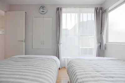 a white bedroom with two beds and a window at Entire Home in Sangenjaya, 2-stops to Shibuya, and Shinjuku, Lani's Place at Sangenjaya in Tokyo