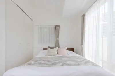 a white bedroom with a bed with pillows and a window at Entire Home in Sangenjaya, 2-stops to Shibuya, and Shinjuku, Lani's Place at Sangenjaya in Tokyo