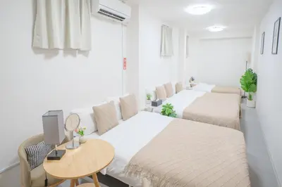 a bedroom with two beds and a table at 3 minutes to Shinjuku by subway-Nakanokaikan I in Tokyo
