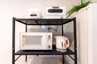 a black shelf with a microwave and a toaster oven at \u5343\u5c0b 130t in Tokyo