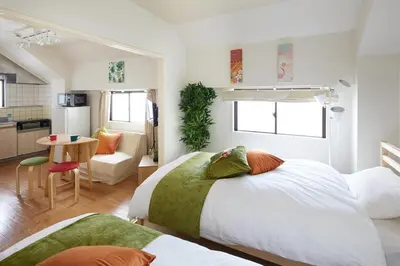 a bedroom with two beds and a table and a kitchen at K&H立石5丁目m305 in Tokyo