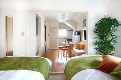 a bedroom with two beds and a living room at K&H立石5丁目m305 in Tokyo