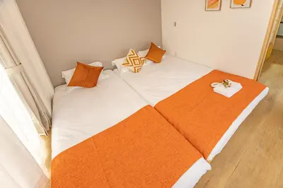 a large bed with orange and white pillows on it at Asakusa Cozy Japanese House with Tatami & Projector, 5min to Station in Tokyo