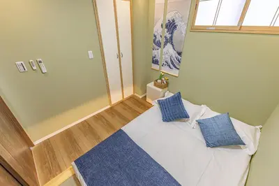a bedroom with a white bed with blue pillows at 7 min walk from JR Yamanote Line Uguisudani Spacious 4-Bedroom House near Ueno & Asakusa With Parking in Tokyo