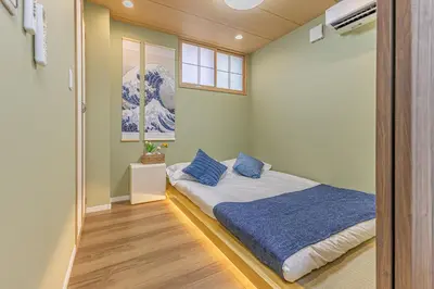 a bedroom with a bed with blue pillows on it at 7 min walk from JR Yamanote Line Uguisudani Spacious 4-Bedroom House near Ueno & Asakusa With Parking in Tokyo