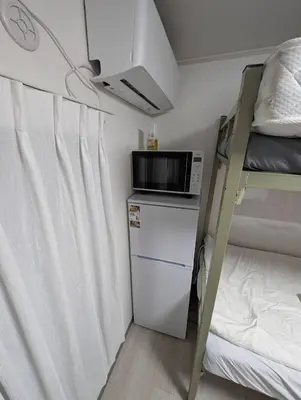a small room with a microwave and a bunk bed at SunRise STAY Minamidai\u4e2d\u91ce\u5357\u53f0 in Tokyo