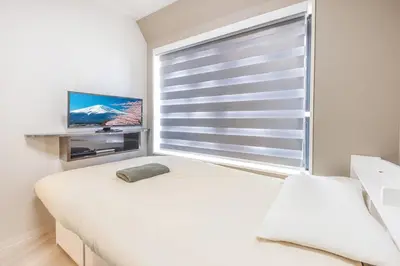 a bedroom with a bed and a window with a television at 201 Direct access to Narita Haneda 5-minute walk to Keikyu Kamata Station, with kitchen, ideal for telework, apartment in Tokyo