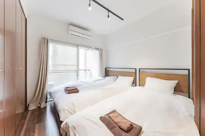 two beds in a white room with a window at Shibuya E-address 205 in Tokyo
